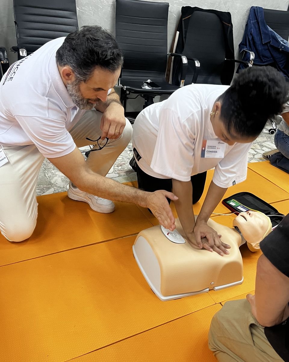 Instrutor da Pulso orientando uma participante na massagem cardíaca em manequim durante treinamento